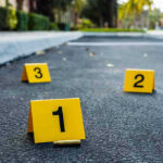 Crime scene markers on asphalt with bullet casing.