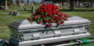Silver casket with rose bouquet in a cemetery.