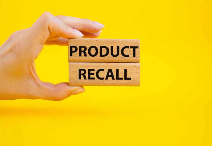 Hand holding Product Recall blocks on yellow background.