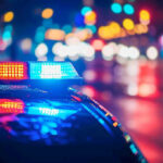 Cops Raid Home Over Facebook Post – Free Speech Under Attack Police car with flashing lights at night.