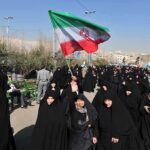 Iran on the Brink: Regime Fires on Its Own People Group of women in black attire marching with an Iranian flag
