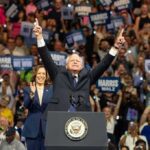 A political leader gestures enthusiastically at a rally with a supportive crowd