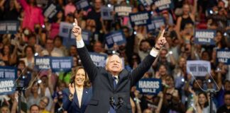 A political leader gestures enthusiastically at a rally with a supportive crowd