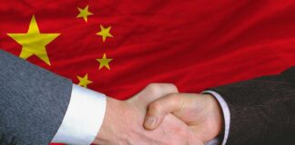 Two hands shaking in front of the Chinese flag