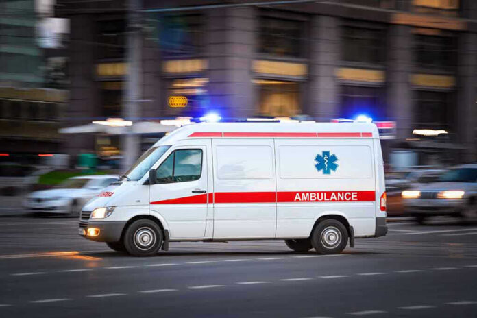 Ambulance driving on urban street with lights flashing.