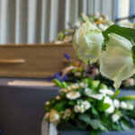 White roses in front of a casket.