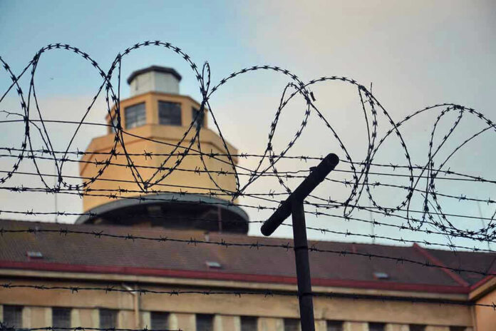 356278409 Barbed wire in front of a prison tower.