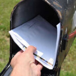 Govt Error Drains $20K From Woman’s Account! Hand placing mail in a black mailbox.