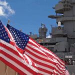 Trump’s Blitz PAUSED After Iran’s DESPERATE Request American flags in front of a naval ship under a blue sky