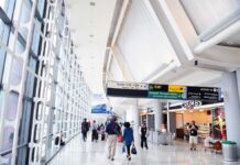 Feds Turn U.S Airports Into Medical Checkpoint! Interior of an airport terminal with travelers and signage