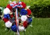 Honorary Servicewoman Event CANCELED! – See Why! A patriotic memorial wreath adorned with red, white, and blue flowers