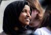 A woman wearing a black hijab smiling at an outdoor event
