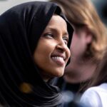 A woman wearing a black hijab smiling at an outdoor event