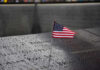 American flag on a rainy memorial nameplate.