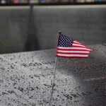 American flag on a rainy memorial nameplate.