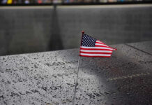 9/11 Families Rebel: Order Muslim Mayor Stay Clear American flag on a rainy memorial nameplate.
