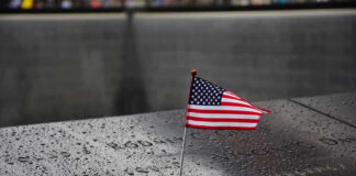 American flag on a rainy memorial nameplate.