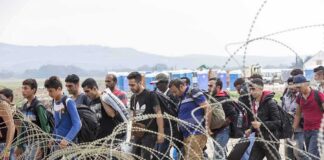 Group of people walking past barbed wire