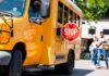 School bus with extended stop sign near students on sidewalk