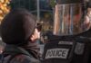 protester faces police officer in riot gear
