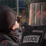 protester faces police officer in riot gear