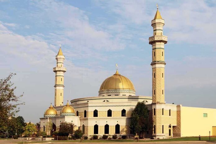 Mosque with golden dome and two tall minarets under a partly cloudy sky