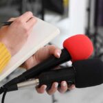 President Spotted ALIVE at Khamenei Funeral After He Was ‘Dead’ in Strikes Journalist holding two microphones while writing in a notebook