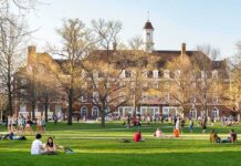 Two Sudden Deaths Rattle College Campus Students relaxing on a campus quad in front of a brick academic building
