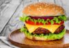Burger Icon Closes Hundreds of Locations – Beef Crisis! Cheeseburger with lettuce, tomato, and onion on a wooden plate