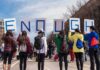 Group of people holding signs spelling ENOUGH at a street protest