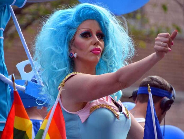 shutterstock_1162641679 Drag performer with bright blue wig giving thumbs up at parade