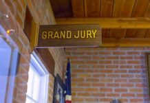 Juror TARGETED For Being A Republican Grand jury sign in a brick-walled hallway