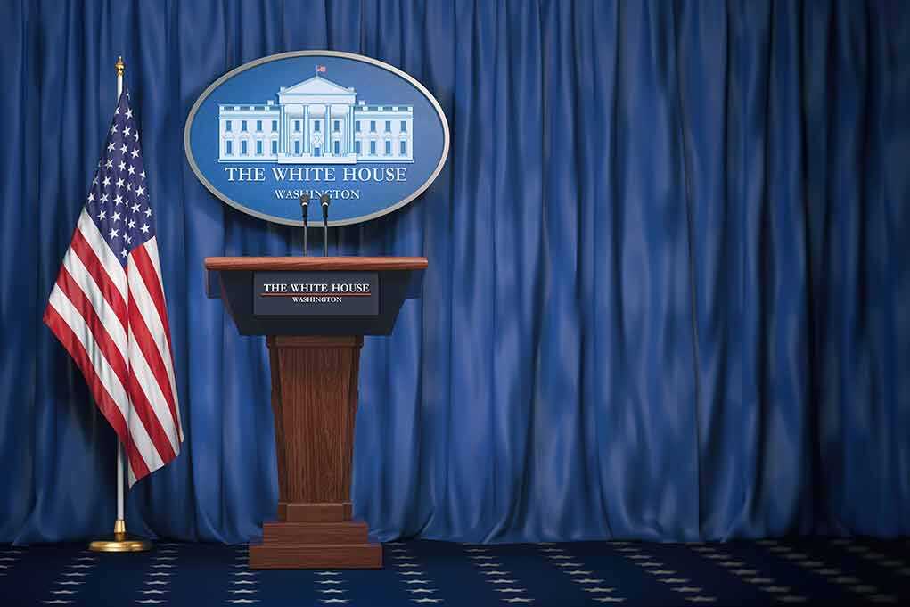 Trump Launches TV Channel Amid Media Blackout White House press briefing podium with U.S. flag and blue curtain