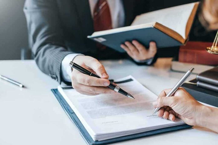 Hands signing a legal document at a desk