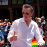 CREEPY Dem Rep Campaigned With 11 YEAR-OLD Child Drag Queen Gavin Newsom gives a thumbs-up at a parade; Teddy Williams stands nearby in a crowd