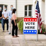 Wacky Marxist Concedes After Gubernatorial Primary Voters wearing masks line up outside a polling place
