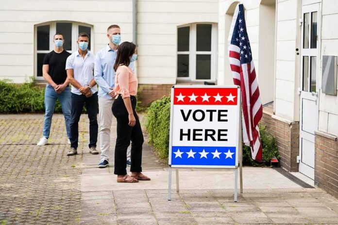 shutterstock_1772910065 Voters wearing masks line up outside a polling place
