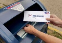 Person mailing a ballot into a blue street mailbox
