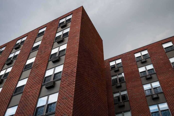 Brick apartment buildings with window air conditioners under cloudy sky