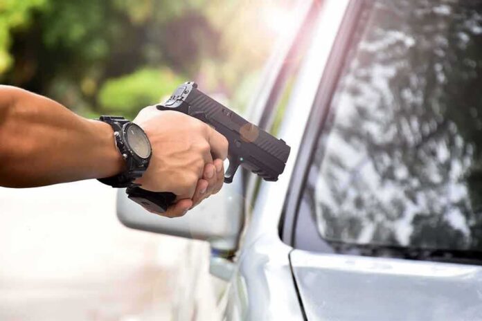 hands holding a handgun aimed near a car window