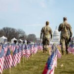 Chilling Code Found on National Mall Lawn! Two soldiers walk among American flags toward the U.S. Capitol