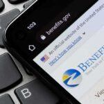 smartphone showing Benefits.gov website on a laptop keyboard