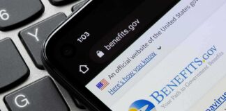 smartphone showing Benefits.gov website on a laptop keyboard