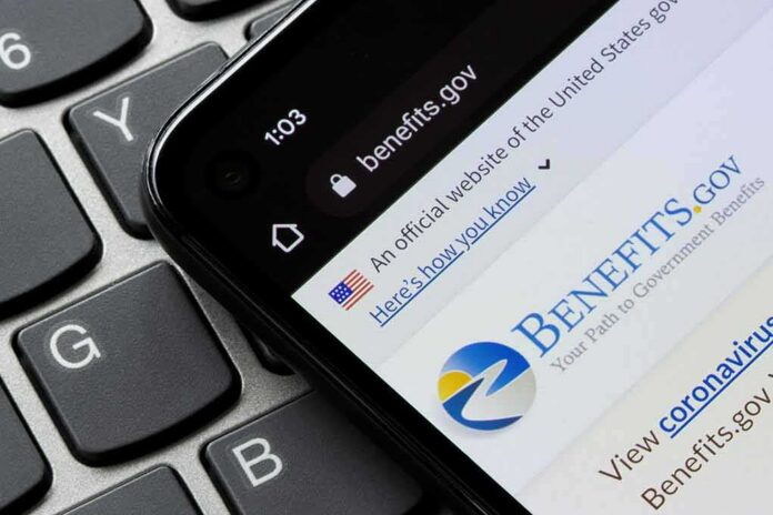 smartphone showing Benefits.gov website on a laptop keyboard