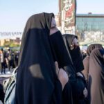 Women in black veils standing in a crowded outdoor gathering