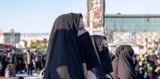 Women in black veils standing in a crowded outdoor gathering