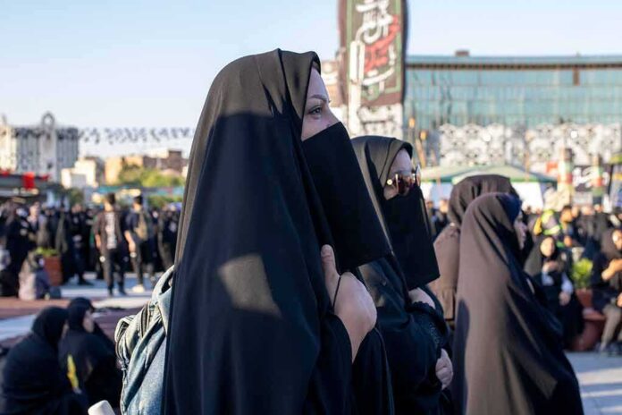 shutterstock_2203213811 Women in black veils standing in a crowded outdoor gathering