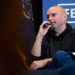Bald man in a hoodie speaking into a microphone