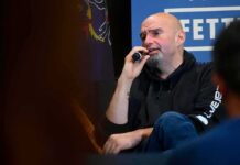 Bald man in a hoodie speaking into a microphone