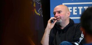 Bald man in a hoodie speaking into a microphone